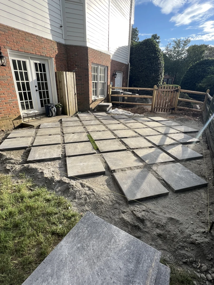 Geometric paving installation in progress beside a home