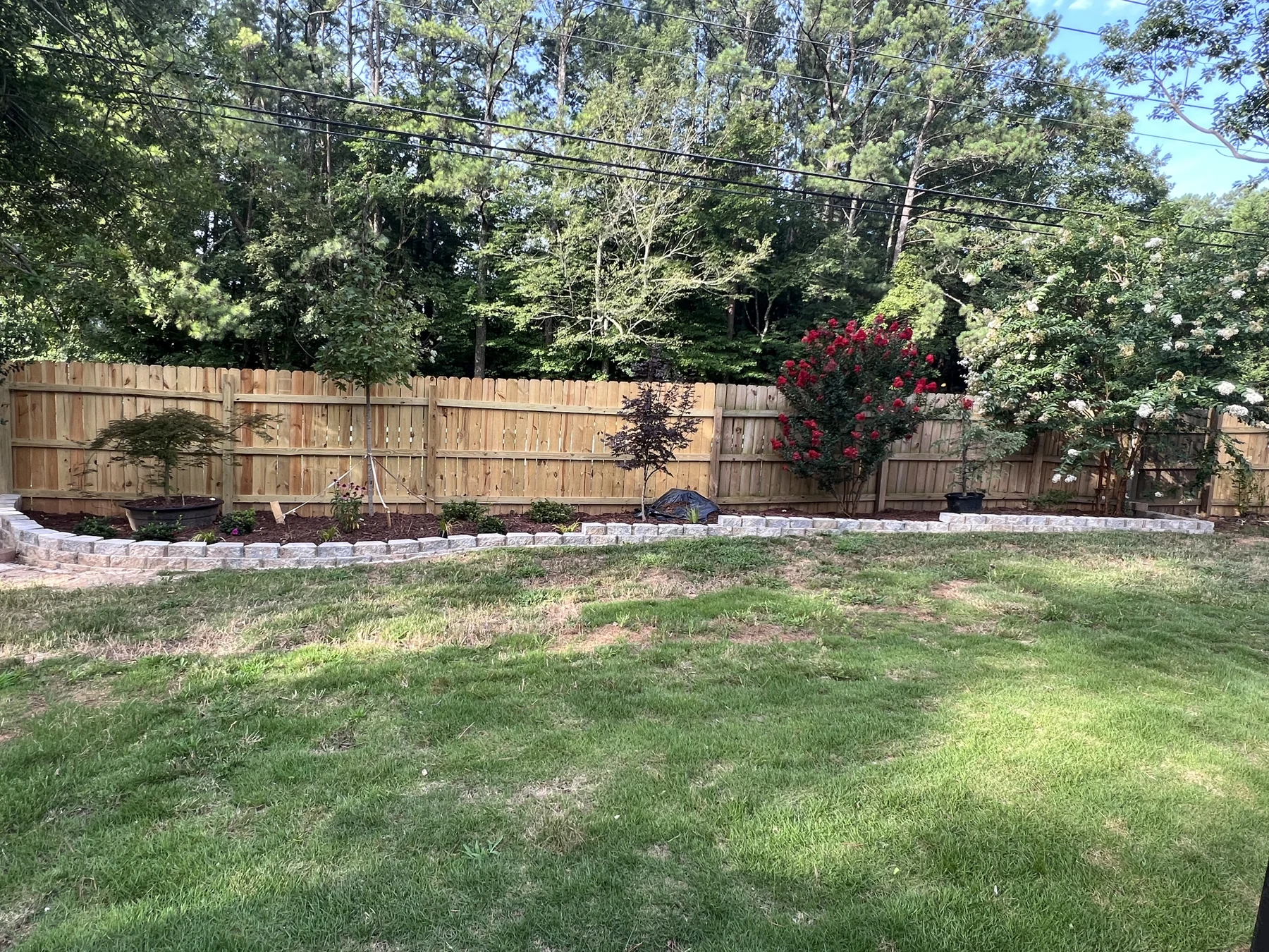 Garden with a lawn, stone-edged planting beds, and a wooden fence